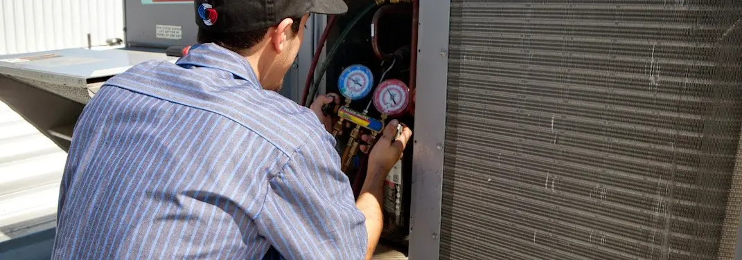 HVAC technician servicing a condenser unit in Blythewood